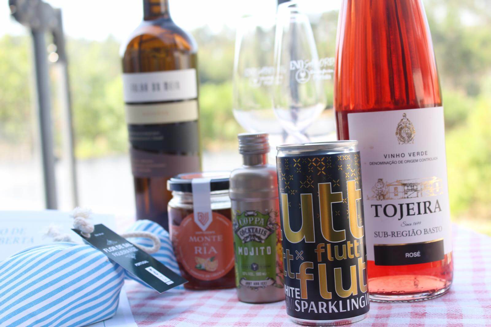 Selection of drinks including wine and sparkling beverage, presented on a checkered table outdoors.